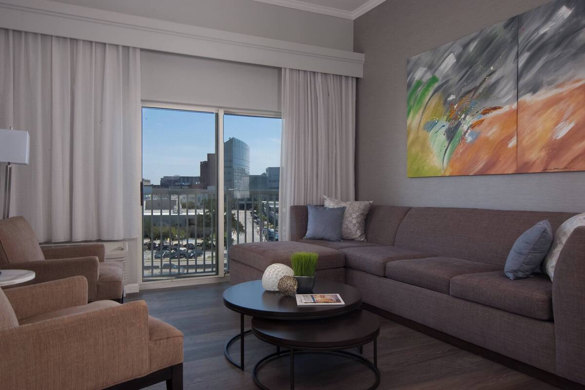 A modern living room with a brown sofa, a round coffee table, and a large abstract painting.