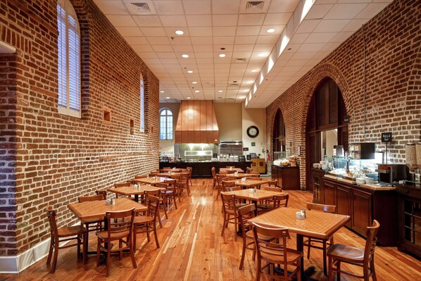 A restaurant with brick walls, wooden tables, and a central counter.