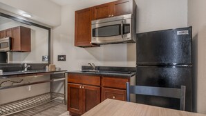 A compact kitchen with a microwave, refrigerator, and wooden cabinets.
