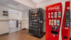 A hotel lobby with a vending machine and a Coca-Cola dispenser.