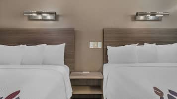 Two beds with headboards, a nightstand, and a wall-mounted light fixture.