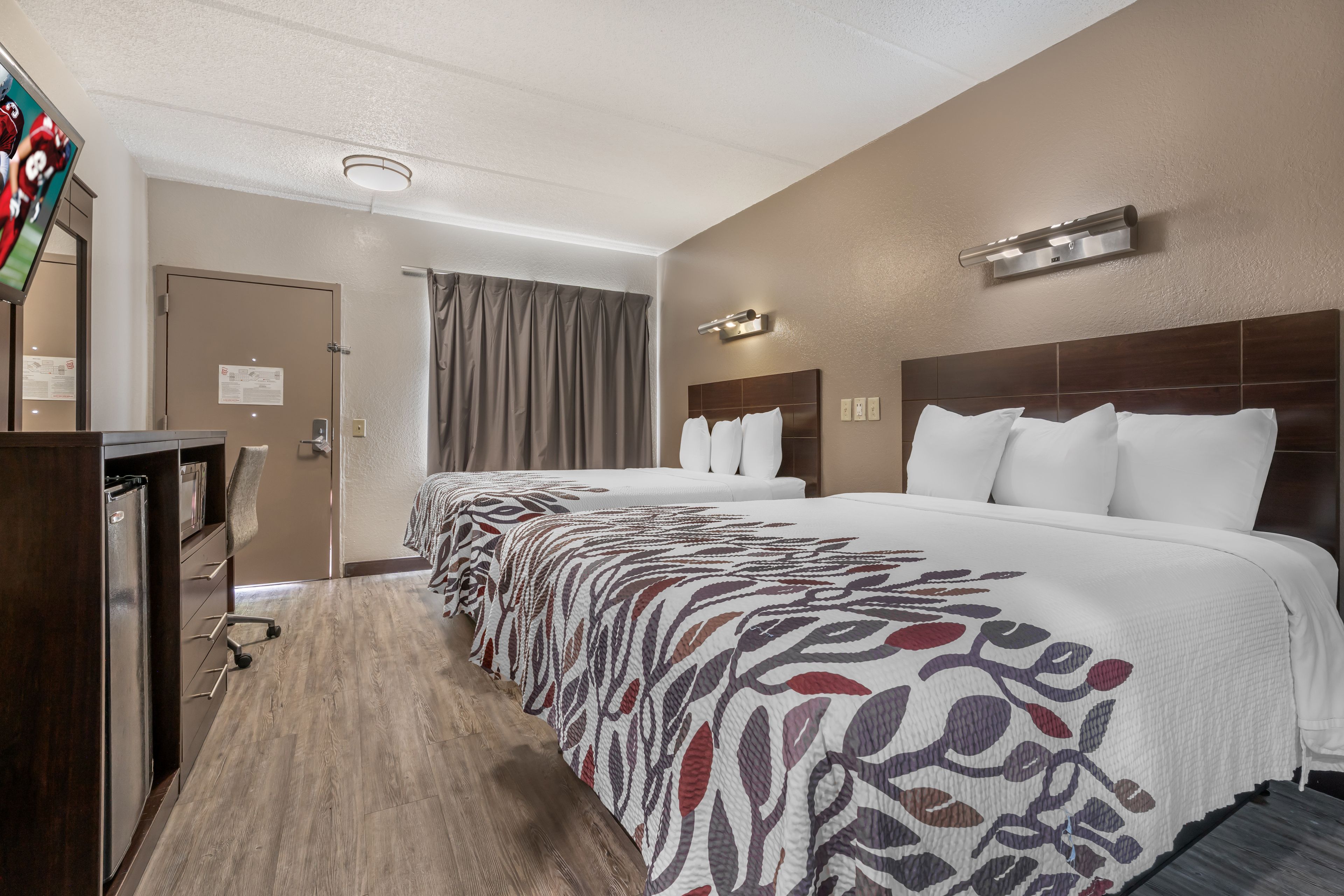 A hotel room with a large bed, a desk, and a television.
