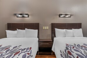 A hotel room with two beds, each with a headboard, a nightstand, and a wall-mounted light fixture. - Red Roof Inn Houston - Brookhollow (Houston)