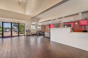 A hotel lobby with a reception desk, seating area, and a view of the parking lot.