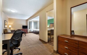 Una habitación de hotel con escritorio, silla, cómoda y televisor.