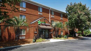 Un hôtel de la chaîne Stay America avec une façade en briques, un hall d’entrée et un parking.