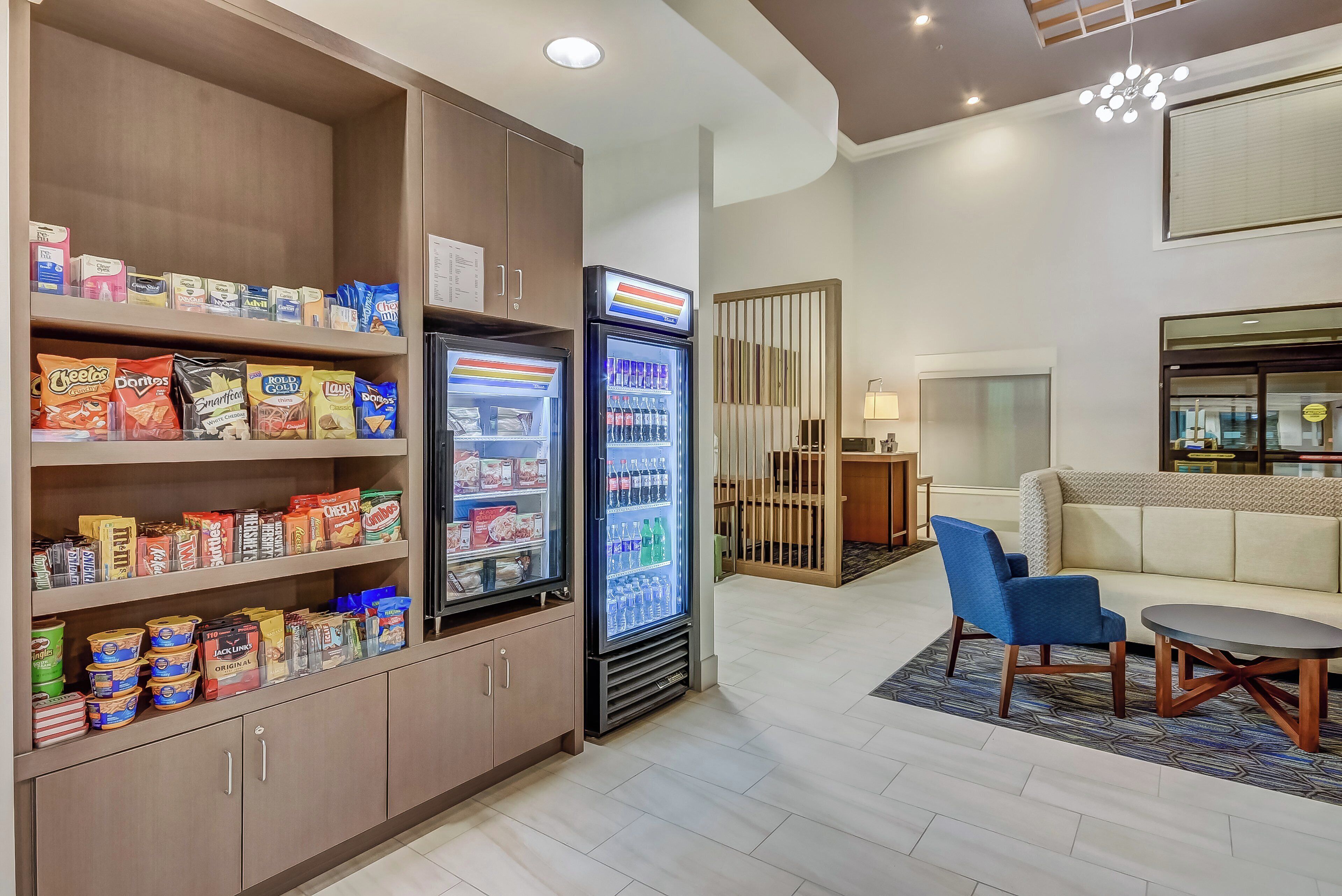A hotel lobby with snack vending machines, a seating area with a sofa and chairs, and a small table.