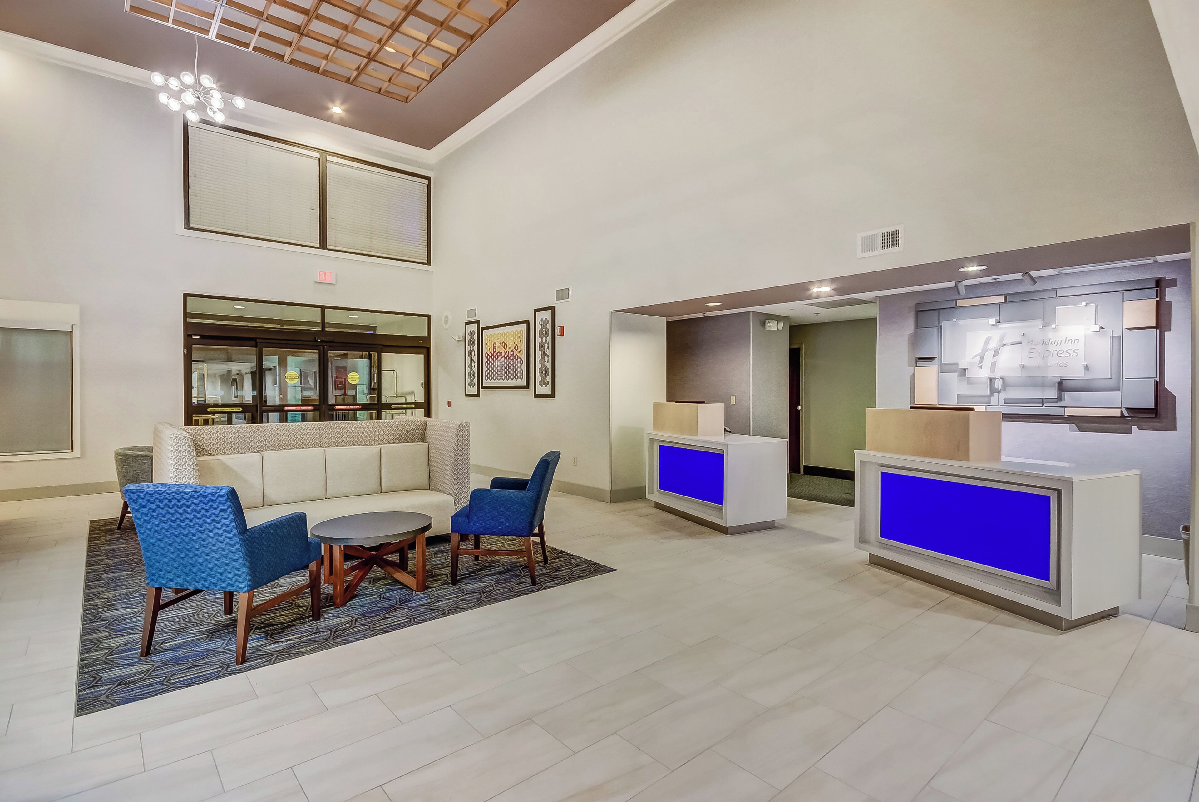 Un hall d’hôtel comprenant un comptoir d’accueil, un espace salon et un plafond haut orné de motifs en bois.