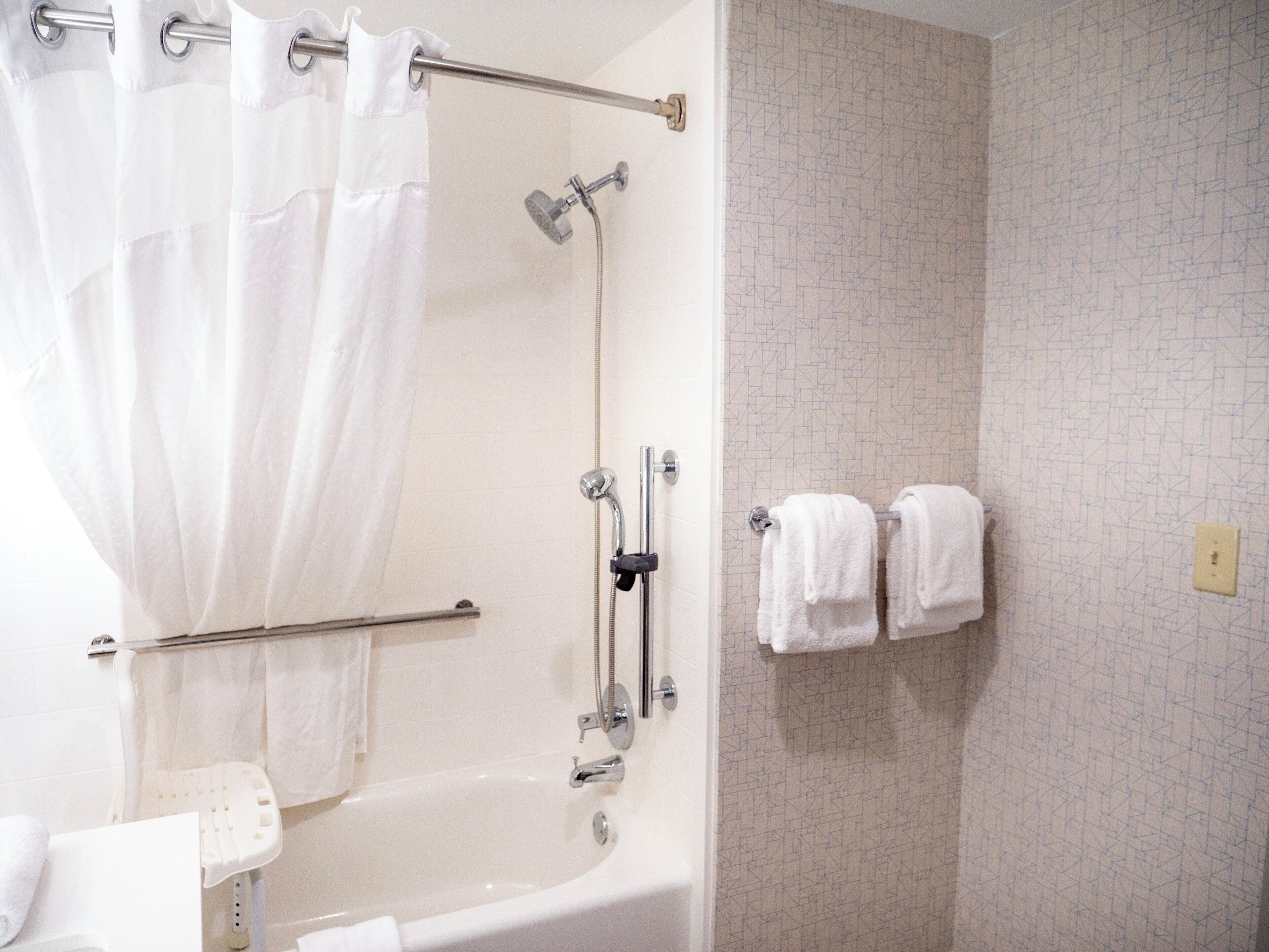 A bathroom with a bathtub, a shower, and a towel rack with two towels.