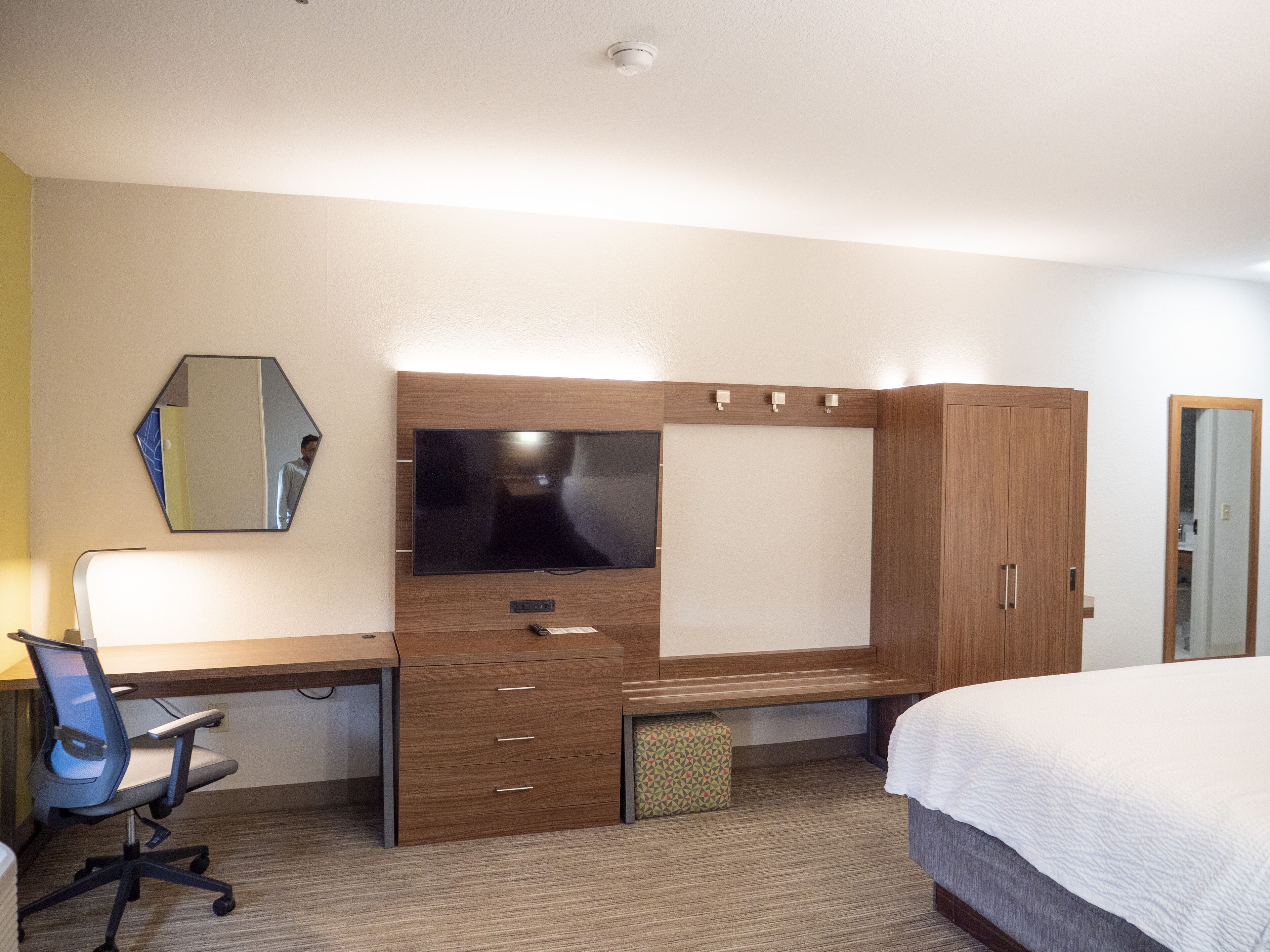 Une chambre d’hôtel comprenant un lit, un bureau avec une chaise, une télévision, une armoire et un miroir.