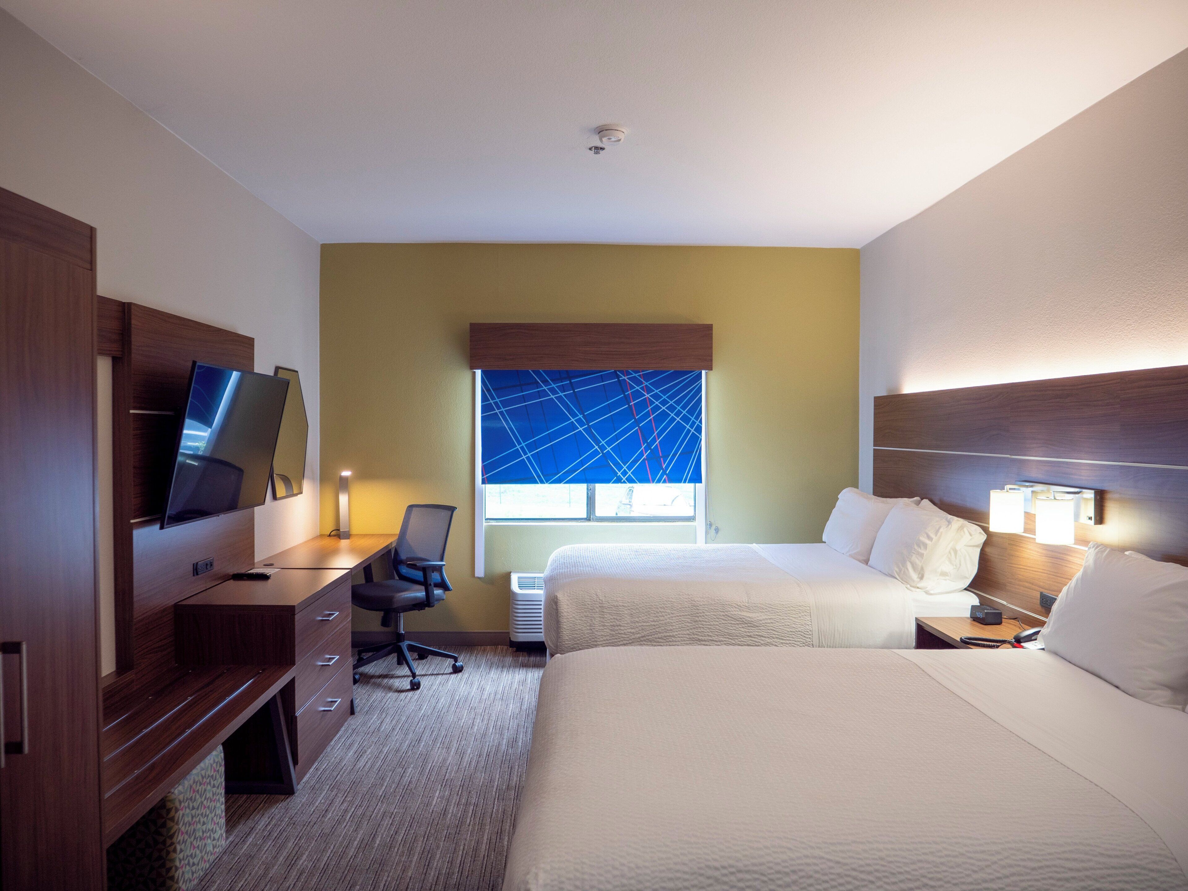 Een hotelkamer met een bed, een bureau met stoel, een televisie en een raam met uitzicht.
