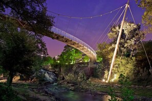 A suspension bridge over a river with a waterfall, surrounded by trees and rocks. - Holiday Inn Express & Suites Greenville Airport by IHG (Greer)