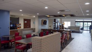 A spacious indoor area with a seating area, a counter with a coffee machine, and a refrigerator.