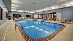 An indoor swimming pool with a clear blue water, surrounded by lounge chairs and a tiled floor. - Holiday Inn Express & Suites Greenville Airport by IHG (Greer)
