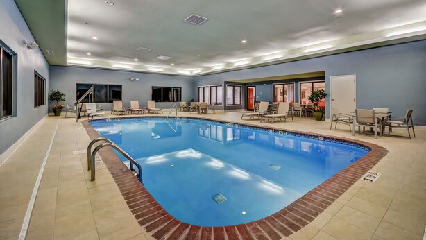 An indoor swimming pool with a clear blue water, surrounded by lounge chairs and a tiled floor. - Holiday Inn Express & Suites Greenville Airport by IHG (Greer)