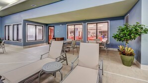 A spacious indoor seating area with tables and chairs, large windows with blinds, and a potted plant. - Holiday Inn Express & Suites Greenville Airport by IHG (Greer)