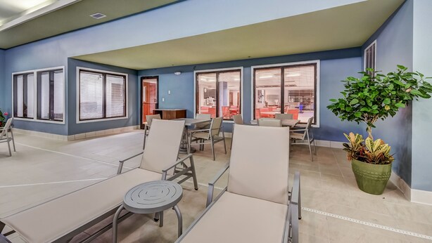 A spacious indoor seating area with tables and chairs, large windows with blinds, and a potted plant. - Holiday Inn Express & Suites Greenville Airport by IHG (Greer)