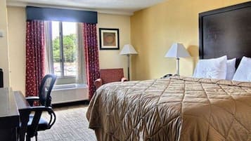 A hotel room with a large bed, a desk, a chair, a lamp, and a window with curtains.