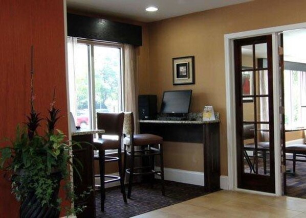 A room with a desk, computer, chairs, a window, and a door.