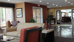 A lobby with a reception desk, a sofa, a coffee table, and a patterned carpet. - Quality Inn & Suites Greenville near downtown (Greenville)