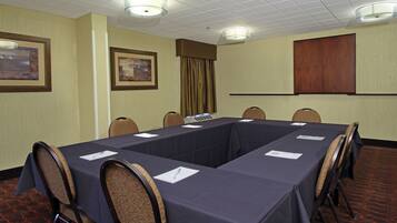 Un salón de conferencias con una larga mesa, sillas y cuadros en las paredes.