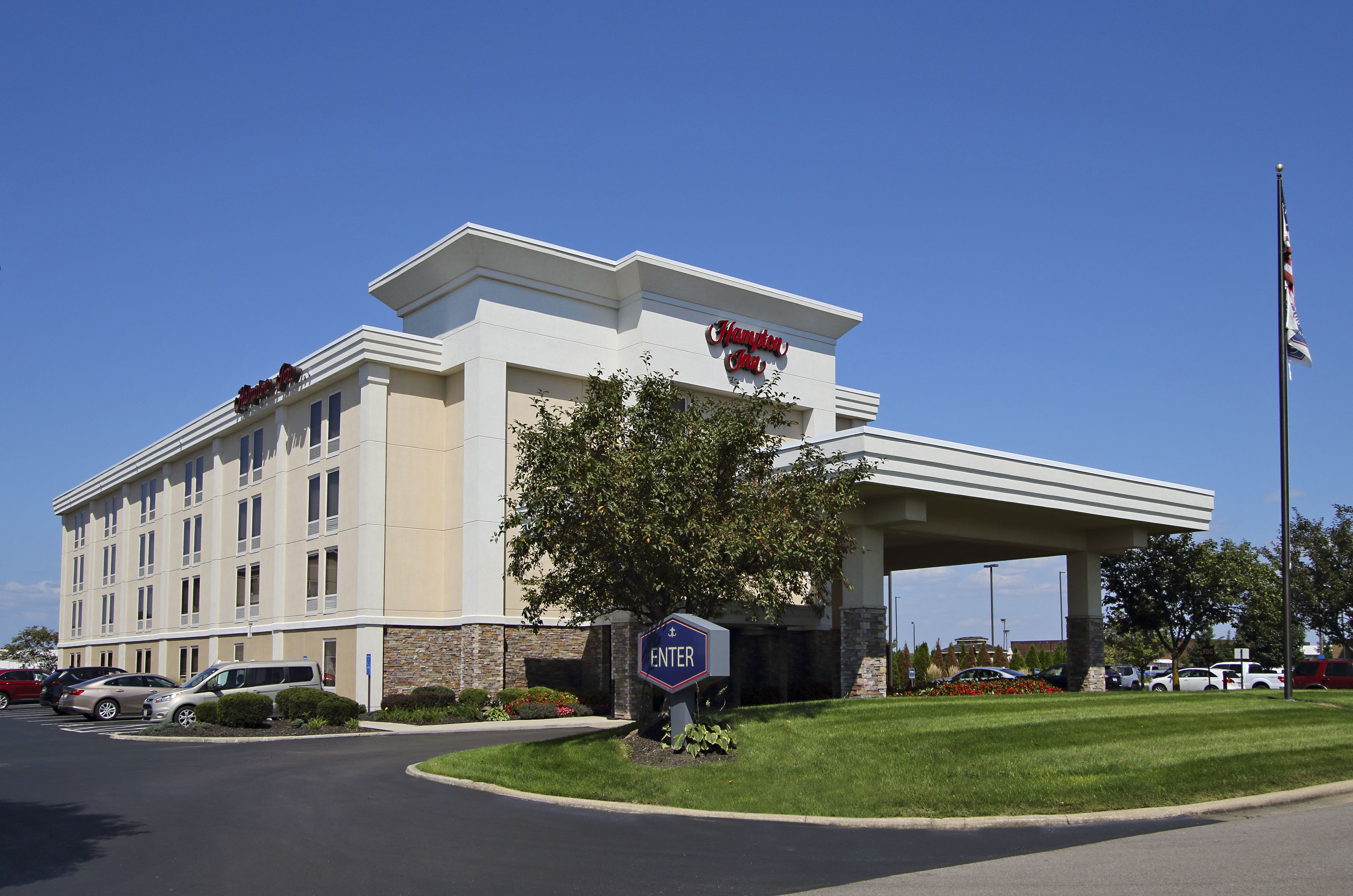 A Hampton Inn hotel with a clear entrance, parking area, and a flagpole.