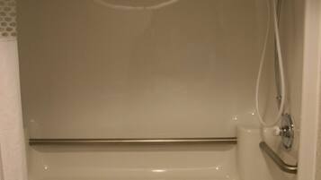 A white bathtub with a handheld showerhead and a handheld faucet.