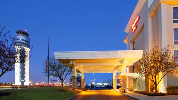 A hotel entrance with a modern design, a prominent tower, and a well-lit driveway.