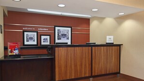 A reception desk with a wooden panel design, framed welcome signs, and a sign indicating the hotel name.