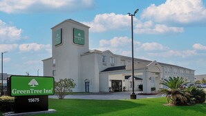 Ein GreenTree Inn Hotel mit auffälliger Beschilderung, Parkplatz und gepflegtem Rasen.