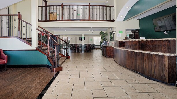 Eine geräumige Lobby mit einer Holztreppe, einem Empfangstresen und einer Sitzecke.