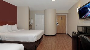 Ein Hotelzimmer mit einem Bett, einem Fernseher, einer Mikrowelle und einer Tür zu einem Badezimmer.
