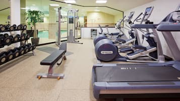 A gym with treadmills, dumbbells, and weight machines.