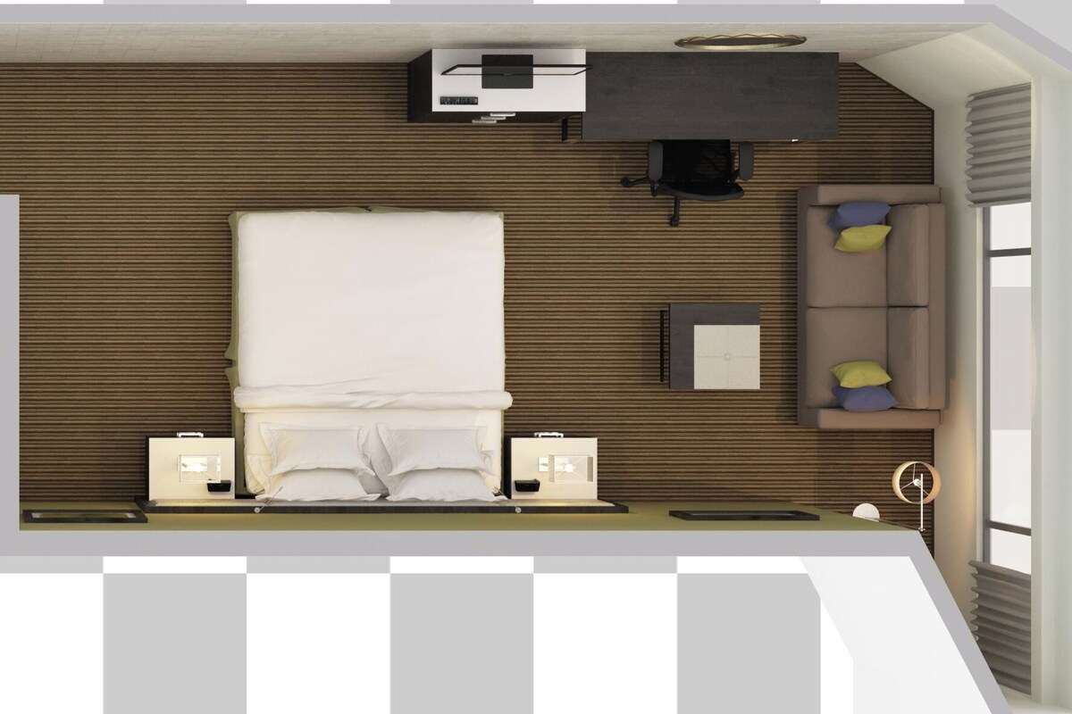 A hotel room layout with a bed, a desk, a chair, a sofa, a small table, a TV, and a bathroom.