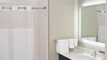 A modern bathroom with a shower, a sink, a mirror, and a towel rack.