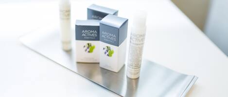 Tres cajas y dos botellas de Aroma Actives Essentials sobre una superficie reflectante.
