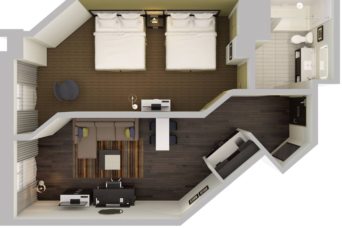 A modern hotel room with a large bed, a sitting area with a sofa and coffee table, a separate bathroom, and a small kitchen area.