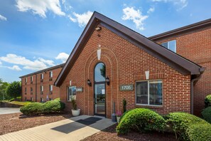 A brick building with a 'Lobby' sign, number 1705, and a clear sky. - HomeTowne Studios & Suites by Red Roof Greensboro (Greensboro)