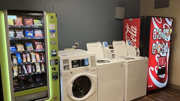 A laundromat with a vending machine, a Coca-Cola vending machine, and two washing machines.