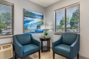 Una habitación con dos sillones azules, un cuadro, una lámpara y una pequeña mesa con una planta.