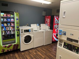 Una sala de lavandería con máquinas expendedoras, lavadoras y un refrigerador de Coca-Cola.