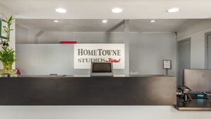 A reception desk with a sign for Home Towne Studios, a Dell computer, and a payment terminal. - HomeTowne Studios & Suites by Red Roof Greensboro (Greensboro)