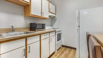 A kitchen with white cabinets, a microwave, stove, and a refrigerator.