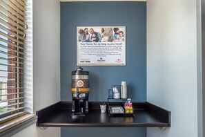 Un letrero en la pared con una foto de familia y texto que promociona servicios de alojamiento en casas particulares, una máquina de café y una bandeja con servicios de cortesía.