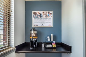 Un letrero en la pared con una foto de familia y texto que promociona servicios de alojamiento en casas particulares, una máquina de café y una bandeja con servicios de cortesía.
