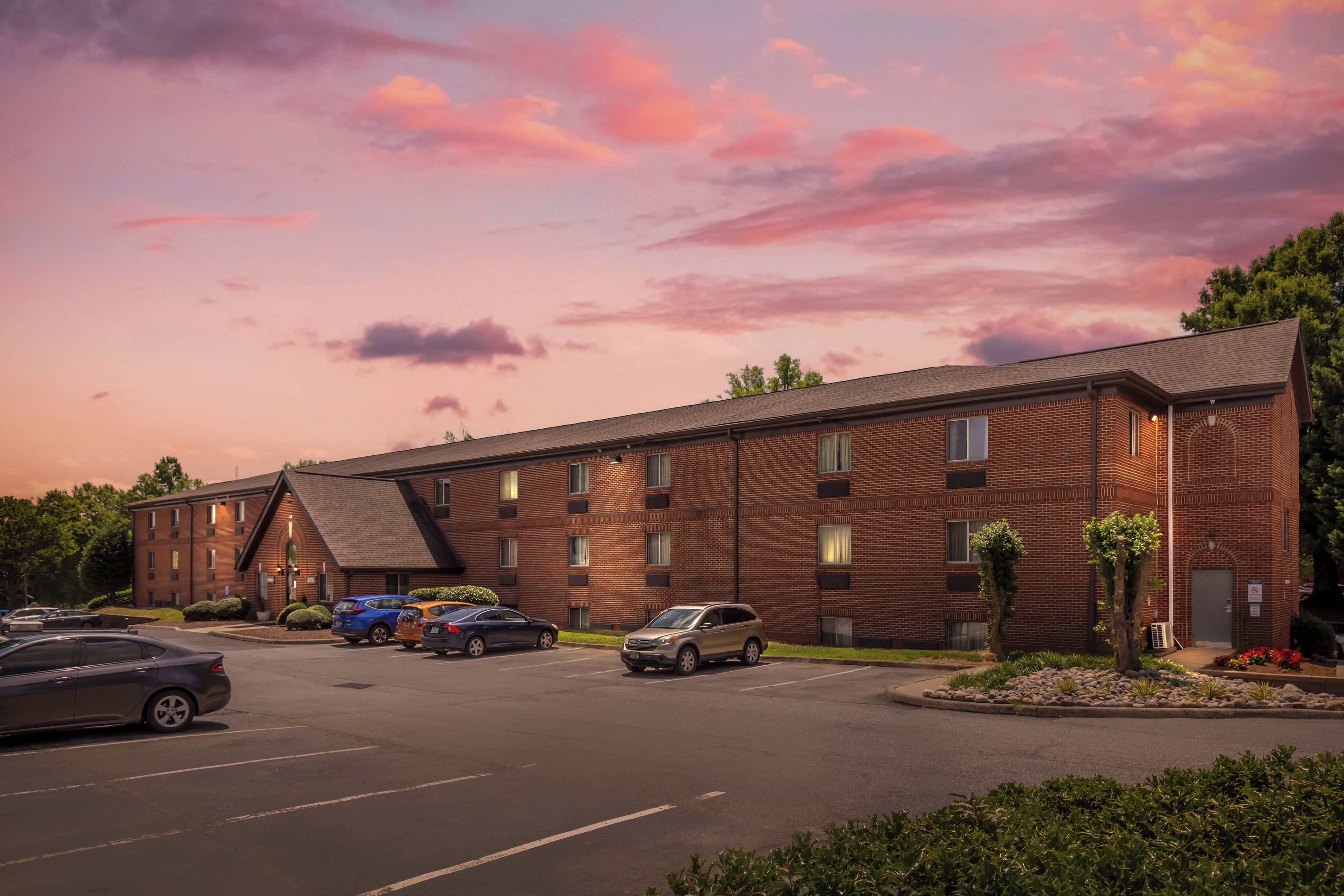 A multi-story brick building with a parking lot in front.