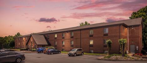 A multi-story brick building with a parking lot in front.