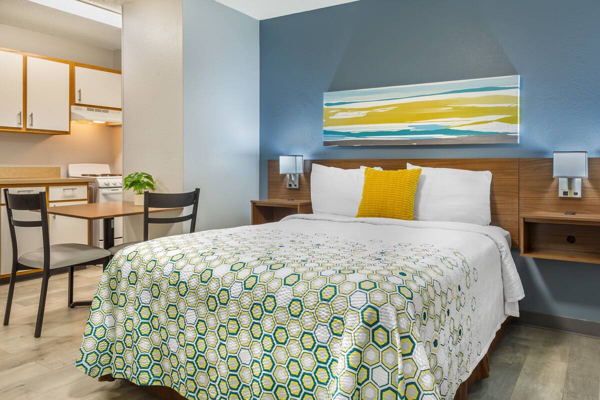 A hotel room with a bed, a desk, and a chair.