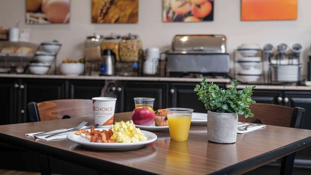 A breakfast table with plates of food, a coffee cup, and a glass of orange juice.