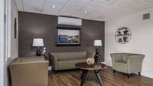 A modern room with a sofa, two armchairs, a round coffee table, and a framed picture on the wall.